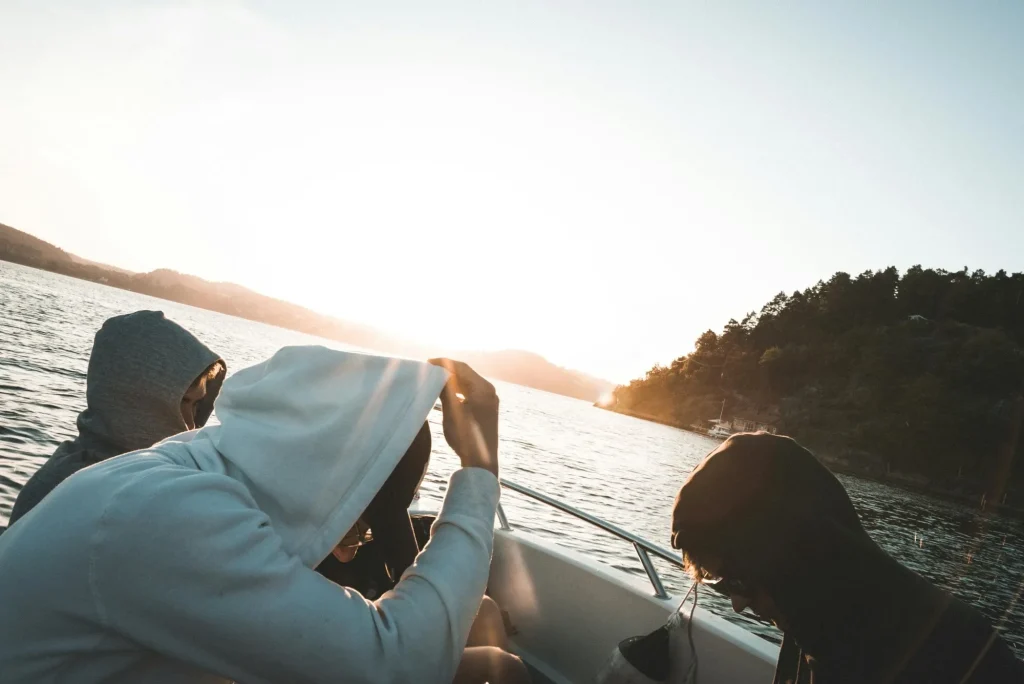 Friends sitting on a boat in hoodies during their boat day.