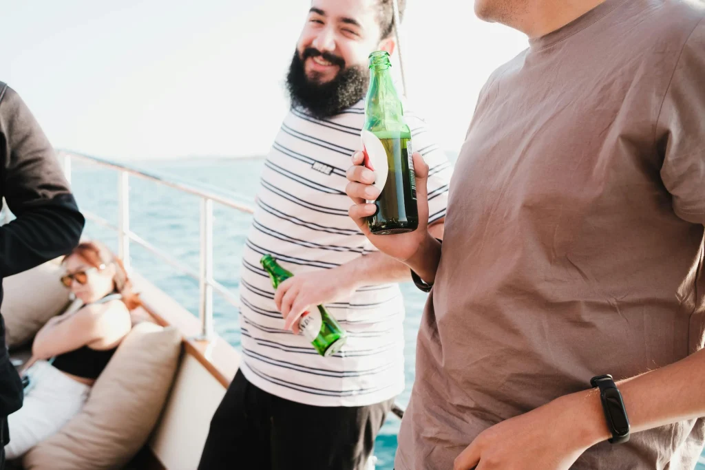 Two men relaxing on a boat deck in casual layers and sunglasses during a sunny day on the water
