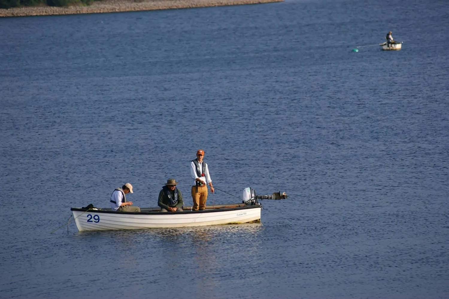 Small flat-bottom boat carrying three people on calm water