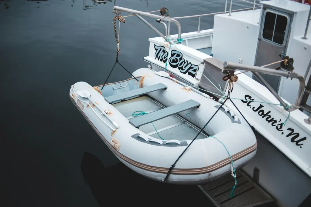 Small inflatable dinghy tied alongside a larger boat in calm water
