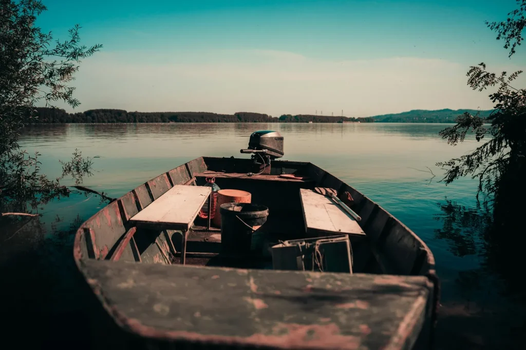 Small aluminum fishing boat moored on a calm lake near the shore