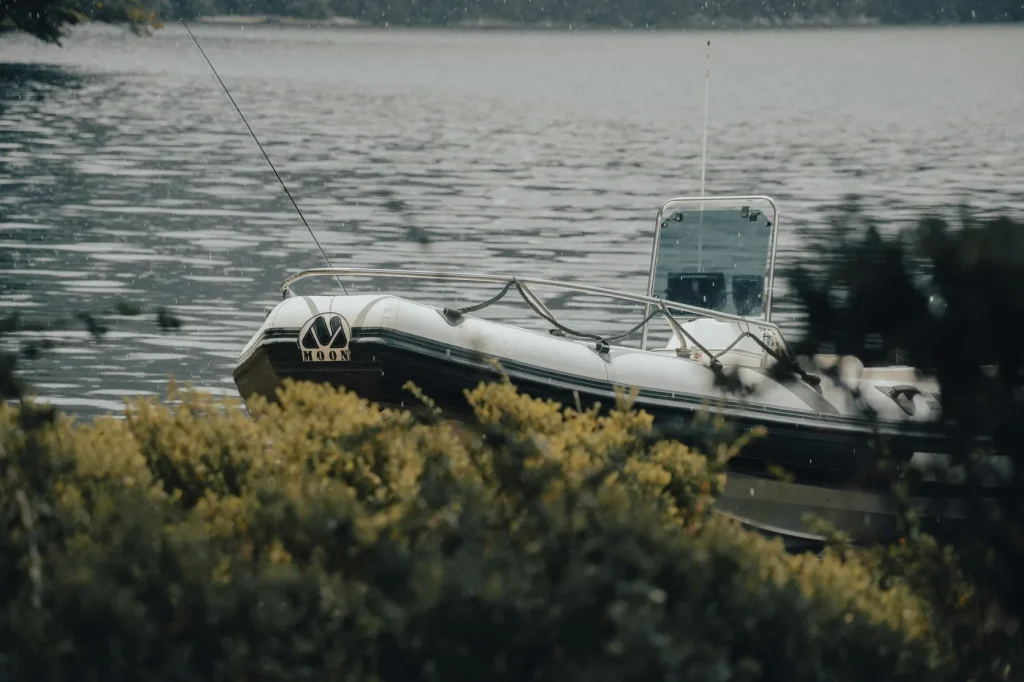 Small rigid inflatable boat moored by the shore on a calm lake